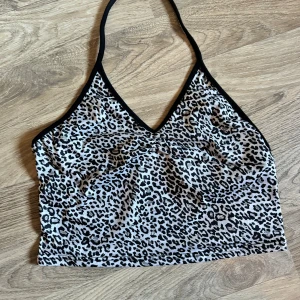 Leopardmönstrad topp från Shein - Säljer en snygg leopardmönstrad topp från Shein. Den är ärmlös och har en halterneck-design med svarta kanter. Perfekt för sommaren och festliga tillfällen! Toppen är i nyskick och har en tight passform. Materialet känns som bomull eller en bomullsblandning. Liten i storlek.