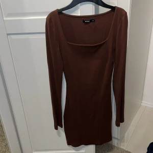 Brun klänning från Bik Bok - Säljer en snygg brun klänning från Bik Bok i storlek XS. Klänningen är långärmad och har en tight passform som framhäver figuren. Perfekt för höst och vinter, och kan stylas både upp och ner beroende på tillfälle. Materialet känns mjukt och bekvämt mot huden.
