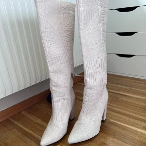 Vita stövlar med krokodilmönster - Säljer ett par snygga vita stövlar med krokodilmönster. De har en spetsig tå och en rejäl klack som ger lite extra höjd. Perfekta för att göra ett statement i vinter! klacken är 9cm ❣️