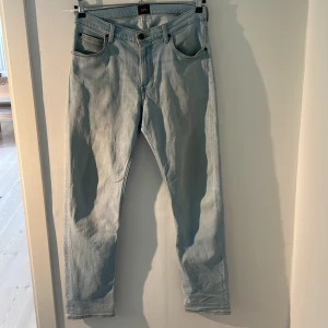 Ljusblå jeans från Lee - Säljer ett par ljusblå jeans från Lee. De har en klassisk femficksdesign och en straight passform. De är i bra skick (9/10) och det finns inga tecken på slitningar, Hör gärna av er vid frågor eller funderingar!