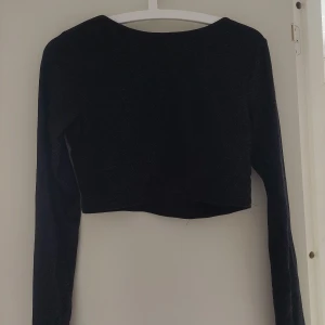 Topp - Glittrig svart topp från Nakd. Croppad med knytning i ryggen.