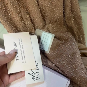Fest klänning  - Denna eleganta Oh Polly-klänning i storlek S är perfekt för baler, bröllop, fester och födelsedagar! Endast använd en gång och i en lyxig rosa nyans med beige ton, ger den en sofistikerad och stilren look som får dig att stråla.