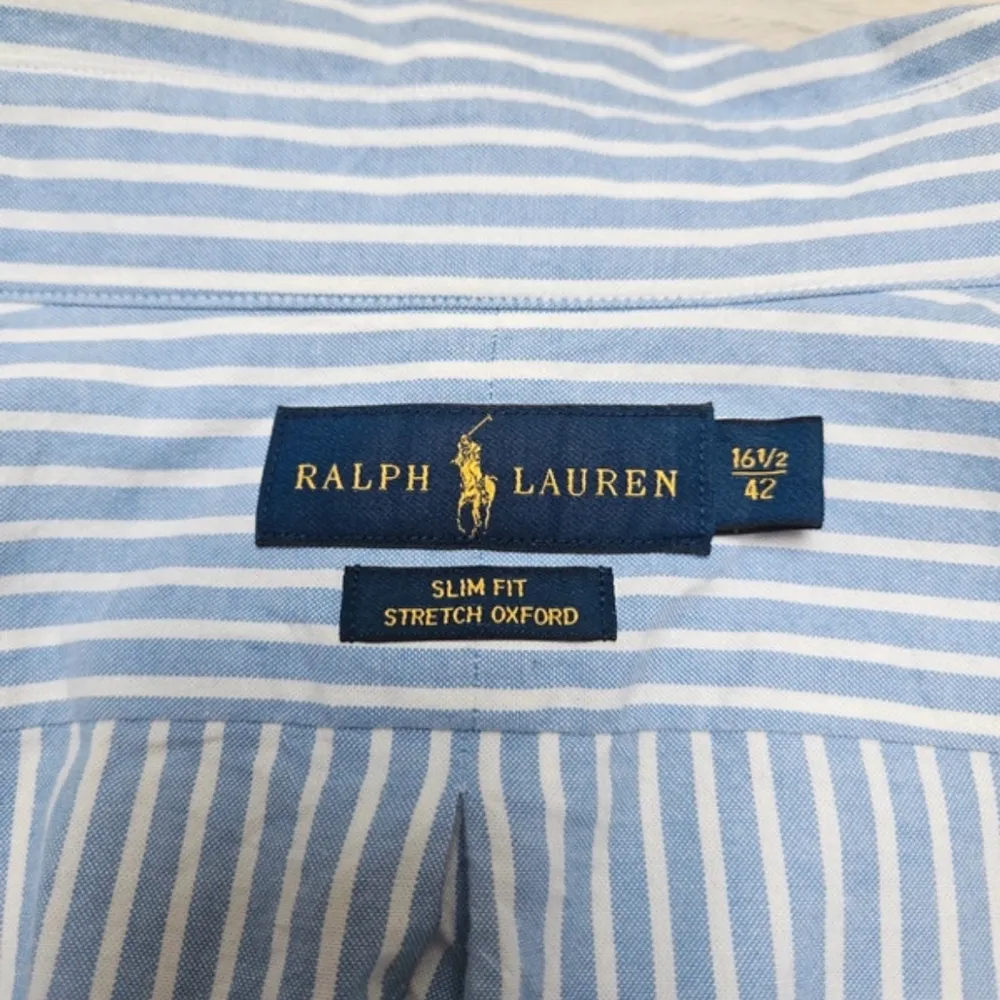 Säljer en klassisk blå och vit randig skjorta från Ralph Lauren. Skjortan är långärmad och har en broderad logga på bröstet. Perfekt för både vardag och fest! Den är i bomull och har en normal passform med knappar framtill.. Skjortor.