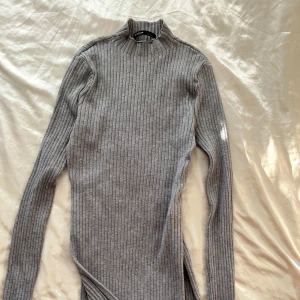 Grå ribbad tröja - Säljer en snygg grå ribbad tröja med lång ärm och hög krage. Den är i nyskick och superbekväm att ha på sig!