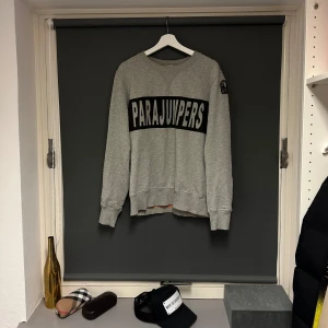 Grå fleece tröja från Parajumpers - Säljer en grå fleece tröja från Parajumpers i storlek M. Den har en stor logga på bröstet och är supermjuk och bekväm. Perfekt för kyliga dagar eller som mysplagg hemma. Tröjan har långa ärmar och en klassisk rund halsringning. Bra skick. Märkeströja. 