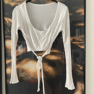 Vit omlottopp med knytband - Säljer en superfin vit omlottopp med långa ärmar och knytband i midjan. Perfekt för både vardag och fest! Materialet är mjukt och bekvämt, vilket gör den idealisk för vår och sommar. Passar perfekt med jeans eller kjol för en chic look.