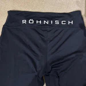 Svarta leggings från Röhnisch - Säljer ett par svarta leggings från Röhnisch i storlek 50/60. De är perfekta för träning med sin bekväma passform och elastiska material. Midjan är hög och ger bra stöd under aktivitet. Passar både till gymmet och yoga.