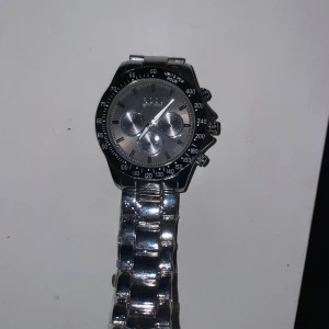 Silverfärgad klocka från Boss - Säljer en stilren och elegant silverfärgad klocka från Boss. Perfekt för både vardag och festliga tillfällen. Klockan är i nyskick alltså aldrig använd och redo att bäras av sin nya ägare. Nytt pris: 2799 kr