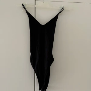 Svart body från H&M  - Svart body med smala band. Svårt att se på bild men det är kryss på ryggen! Aldrig använd. 