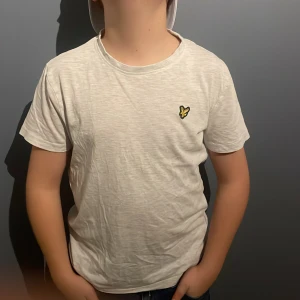 Vit t-shirt med broderad logga - Säljer en vit t-shirt från Lyle & Scott i mycket bra skick. Den har en liten broderad gul logga på bröstet. Perfekt för en avslappnad stil och passar till alla tillfällen. Materialet känns mjukt och bekvämt. PRISET ÄR EJ SKRIVET I STEN!!!