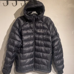 Svart dunjacka från Peak Performance - Säljer en svart dunjacka från Peak Performance i mycket bra skick. Jackan har inga tecken på användning och är endast använd ett par enstaka gånger. Jackan har en stilren design med dragkedja och huva, perfekt för kalla dagar. Den är quiltad och håller värmen bra. Passar både till vardags och utomhusaktiviteter. Storlek L. Orginal pris ligger på 3200kr.