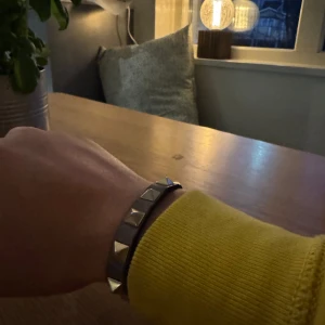 Grått armband med nitar från Valentino - Säljer ett grått armband från Valentino med guldfärgade nitar. Det är justerbart och kommer i originalförpackning. Ett perfekt armband för att ge din outfit en liten extra touch! Bara höra av dig vid minsta lilla intresse! 