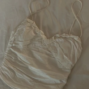 Beige linnetopp från Zara - Säljer en söt beige linnetopp från Zara. Den har smala axelband och en rynkad detalj vid halsringningen. Perfekt för sommardagar eller som ett lager under en kofta. Toppen är i bra skick och redo för nya äventyr!