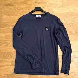 Mörkblå långärmad tröja från Stone Island - Säljer en snygg mörkblå långärmad tröja från Stone Island. Stone Island-märket på bröstet. Perfekt för både vardag och lite mer avslappnade tillfällen. Tröjan är i bra skick och redo för sin andra ägare! Hör gärna av dig om du är intresserad. 