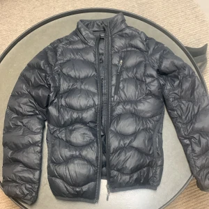 Svart dunjacka från Peak Peformance - Säljer en svart dunjacka från Peak Performance i mycket bra skick. Jackan är perfekt för kyliga dagar med sin quiltade design och dragkedja framtill. Den har långa ärmar och en normal passform, vilket gör den både bekväm och stilren. Perfekt för höst och vinter! Nypris: 2500 kr