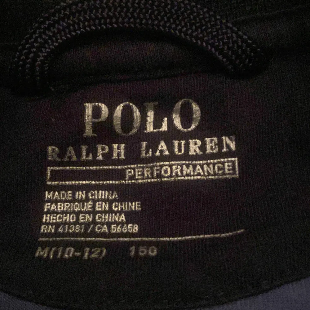 Säljer en snygg college tröja från Polo Ralph Lauren i blått och vitt med coolt kamouflagemönster. Tröjan har långa ärmar och knappar framtill. Den har broderade detaljer med texten 'Football R L Tigers' och en tiger på ryggen. Perfekt för höst och vår!. Tröjor & Koftor.