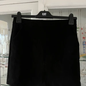 Svart kjol från Vero Moda - Snygg svart kjol från Vero Moda i manchester. Den har en dragkedja bak och är perfekt för både vardag och fest. Kjolen är i bra skick och passar till många olika outfits. Ett måste i garderoben för alla som älskar stilrena plagg!