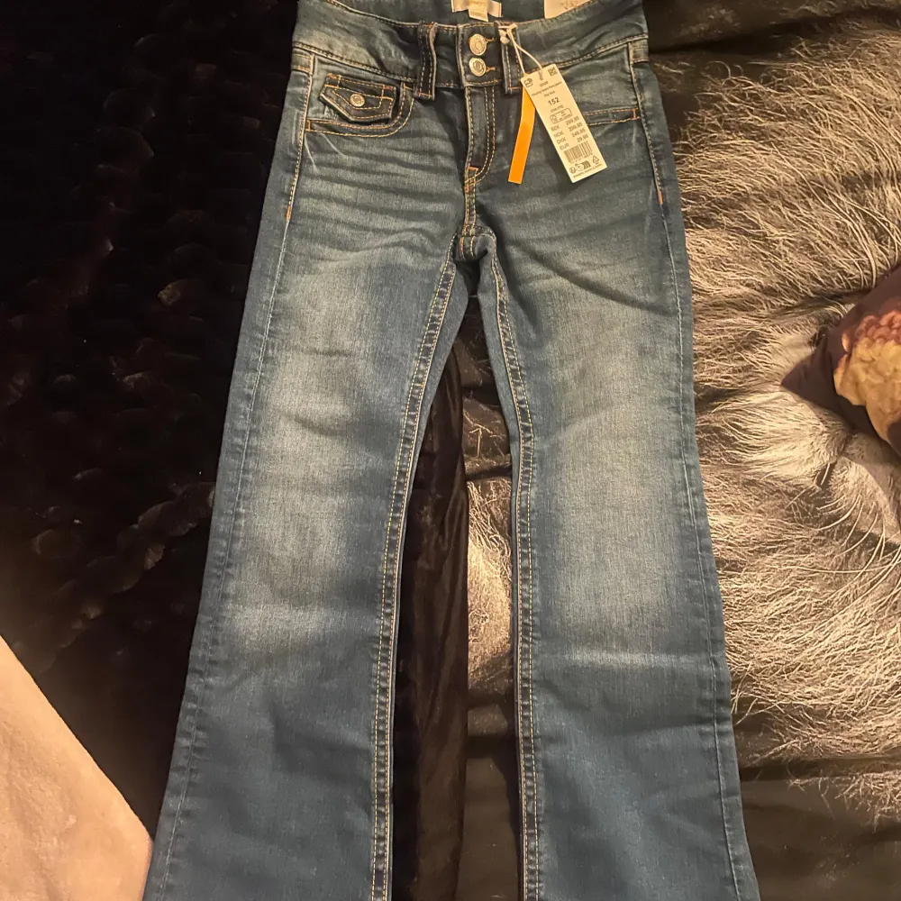 Säljer ett par snygga blå flare jeans från Gina Tricot i storlek 152. De är i nytt skick med etikett kvar. Perfekta för en trendig look med sin bootcut-stil och klassiska jeansmaterial. Passar både till vardags och fest!. Jeans & Byxor.