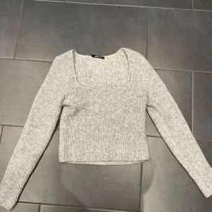 Grå stickad tröja från Gina Tricot - Säljer en superfin grå stickad tröja från Gina Tricot. Den har en fyrkantig halsringning och långa ärmar, perfekt för kyliga dagar. Tröjan är i bra skick och passar både till vardags och lite finare tillfällen. Perfekt för höst och vinter! 🍂