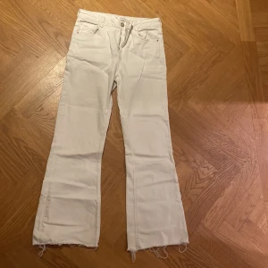 Vita jeansbyxor från MNG - Säljer ett par vita jeansbyxor från MNG i storlek 164 cm, passande för 13-14 år. Byxorna har en bootcut-stil med fransiga kanter och en liten fläck på framsidan. Perfekta för en avslappnad look! 🕶️