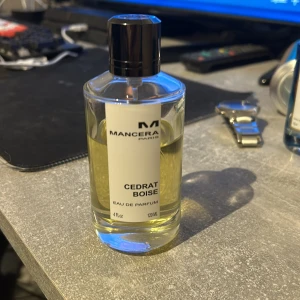 Mancera Cedrat Boise Eau de Parfum - Säljer en flaska Mancera Cedrat Boise Eau de Parfum, 120 ml. Den har en elegant och stilren design med en svart kork och en genomskinlig flaska som visar den ljusgula vätskan. Kommer med originalförpackning och en snygg svart påse. Perfekt för den som gillar fräscha och träiga dofter! Pris går att diskuteras😁