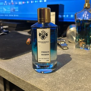 Mancera French Riviera Eau de Parfum - Säljer en flaska Mancera French Riviera Eau de Parfum. Den har en cool blå färg och kommer i en stilren, cylindrisk glasflaska med en guldig kork. Perfekt för dig som älskar fräscha och eleganta dofter. Flaskan är på 120 ml och är nästan full. Passa på att köpa denna lyxiga parfym! Pris går att diskuteras😁
