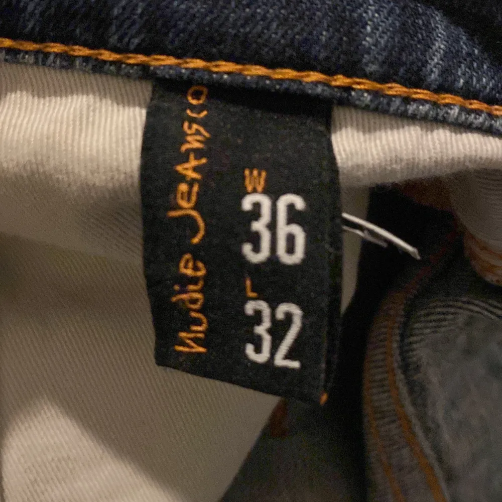 Säljer ett par blå jeans från Nudie Jeans i bra skick med en custom sliten design med färg fläckar på låren som är en del av designen på byxan. Jeans & Byxor.