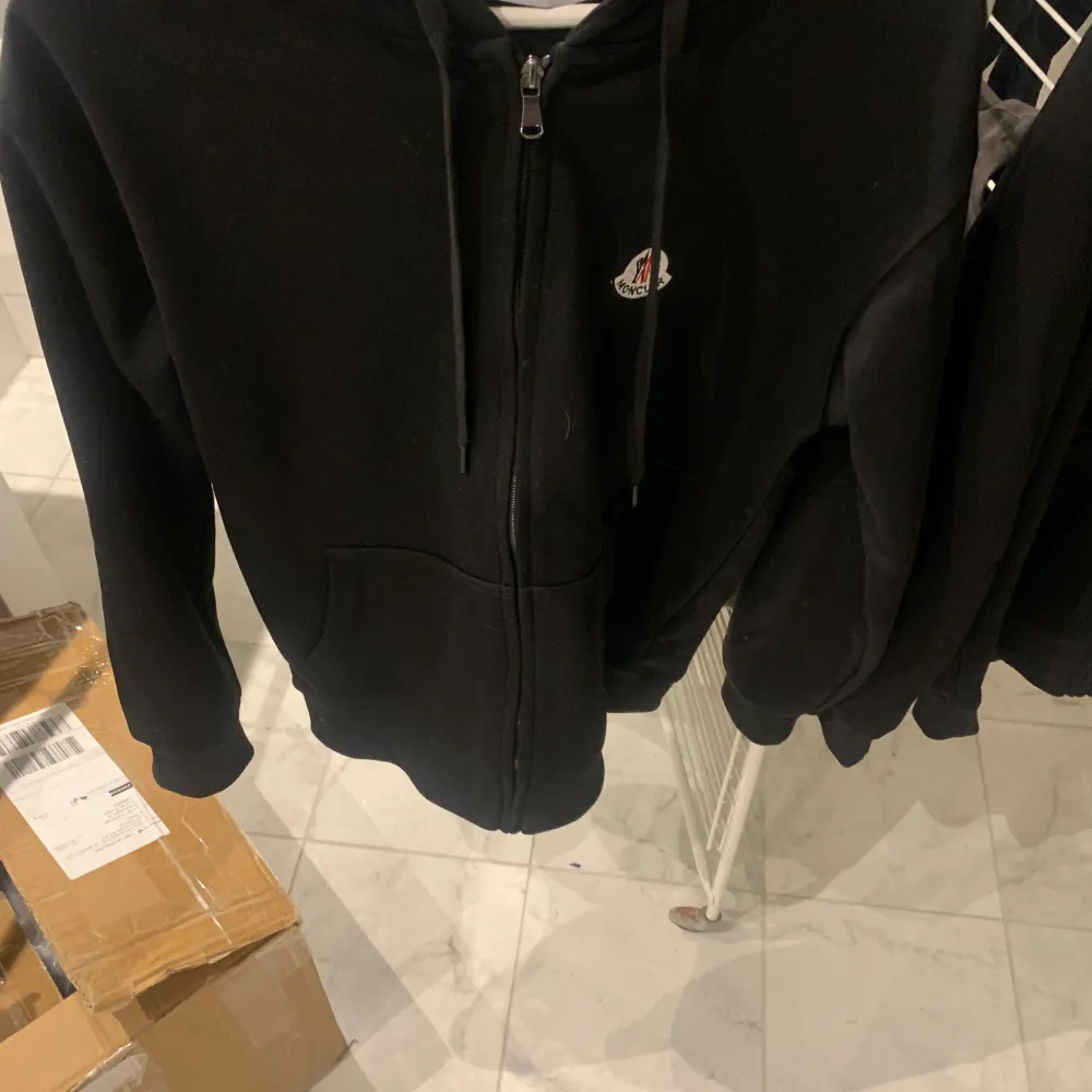 Säljer en svart hoodie från Moncler i mycket bra skick. Den har en dragkedja framtill och en liten Moncler-logga på bröstet. Perfekt för höst och vår, med en stilren och enkel design. Passar både till vardags och lite mer avslappnade tillfällen. Skick10/10. Hoodies.