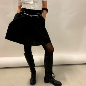 Svart kjol med detaljer - Snygg svart kjol från Miss Happy med coola metallringar och fickdetaljer. Perfekt för en stilren look, passar både till vardags och fest. Kjolen har en A-linjeform och är i ett bekvämt material.