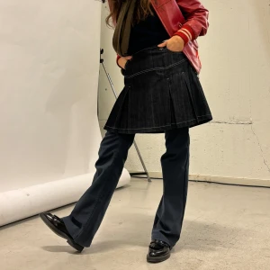 Svart jeanskjol med veck - Säljer en supercool svart jeanskjol med veckdetaljer. Kjolen har en klassisk design med knappar och dragkedja framtill. Perfekt för både vardag och fest! 🖤