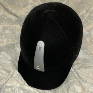 Svart ridhjälm från Kylin - Säljer en snygg och säker svart ridhjälm från Kylin. Den har en stilren design med en silverdetalj framtill. Hjälmen är i mycket bra skick och har en justerbar rem för perfekt passform. Perfekt för ridning och ger ett bra skydd. CE-märkt för säkerhet. Använd några gånger men säljer pga att jag slutat på ridning🩷