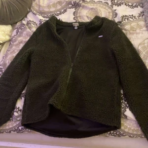 Mörkgrön teddyjacka från aim’n - Mysig olivgrön teddyjacka från aim’n i mycket bra skick. Perfekt just nu när kylan börjar dra in. Dragkedja framtill. Jackan har en normal passform och är långärmad, vilket gör den superbekväm och varm. Ett måste för kalla dagar! 