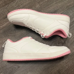 Vita sneakers med rosa detaljer - Säljer ett par snygga vita sneakers med rosa detaljer. De har en klassisk design med snörning och en bekväm passform. Köptes på Primark i Berlin 2022, använda en gång.