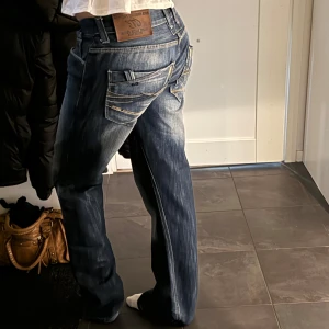 Blå jeans med raka ben - Säljer ett par snygga blå jeans med raka ben och låg midja. De har en klassisk femficksdesign och en cool tvättad look. Perfekta för vardagsbruk och kan enkelt matchas med olika toppar. Passar både till sneakers och boots!