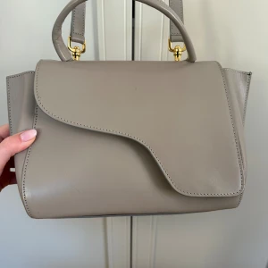 ATP Atelier Arezzo - Väska från ATP Arezzo i ljusgrå färg. Handgjord i Italien av skinn.  Använd, men i bra skick med ett fåtal repor som går att se på första och tredje bilden.  Nypris 5200kr  