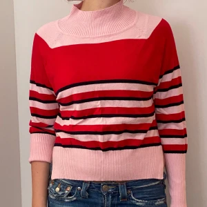 Randig tröja  - Säljer en superfin randig tröja i rött och rosa. Den har en hög krage och långa ärmar, perfekt för höst och vinter. Tröjan är i bra skick och passar både till vardags och lite finare tillfällen. Skön och stilren, ett måste i garderoben! 💖