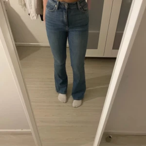 Blå bootcut jeans - Säljer ett par snygga blå bootcut jeans i bra skick. De är högmidjade och har en klassisk femficksdesign med dragkedja och knapp framtill. Perfekta för både vardag och fest! Passar till allt från sneakers till klackar.