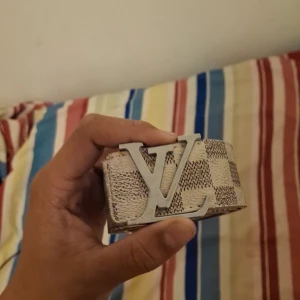 Rutig bälte med silverdetaljer - Säljer ett snyggt bälte med ett rutigt mönster i beige och vitt. Bältet har en stor silverfärgad spänne med en stilren design. Perfekt för att ge din outfit en extra touch. Passar både till vardags och fest!