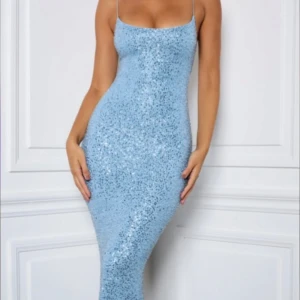 Ljusblå glittrig långklänning - Snygg ljusblå långklänning med glittrande paljetter. Klänningen har en tight passform som framhäver figuren och är ärmlös för en elegant look. Perfekt för speciella tillfällen där du vill glänsa.