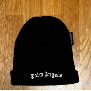 Snygg svart stickad beaniemössa från Palm Angels med broderad logga framtill. Perfekt för att hålla sig varm och stilren under kallare dagar. 