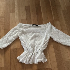Vit spetsblus med trekvartsärm - Säljer en elegant vit spetsblus från Zara med trekvartsärm och offshoulder-design. Blusen har en vacker spetsdetalj och en smickrande passform som passar perfekt för speciella tillfällen.