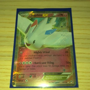 Togekiss EX Pokémonkort - Säljer ett Togekiss EX Pokémonkort med 70 HP. Kortet har attacker som Mighty Wind och Hurricane Wing. Det är en del av serien 83/122 och har en holografisk yta. Perfekt för samlare eller Pokémon-entusiaster! Den har pytte lite vit på kanten men annars är den bra sckick. Så klart är den riktig
