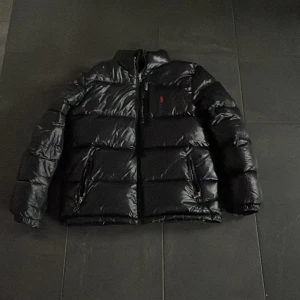 Svart dunjacka - Pris kan diskuteras! Säljer en svart dunjacka med långärmad design. Jackan har en pufferstil och är perfekt för kalla dagar. Den har en dragkedja framtill och är quiltad för extra värme. Perfekt för vintern!