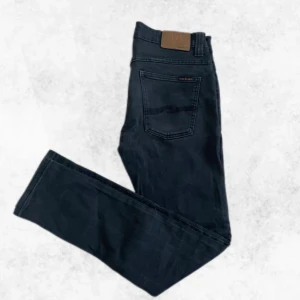 Svarta Nudie Jeans - Säljer ett par svarta Nudie Jeans i modellen Thin Finn. De är i storlek W32 och L33. De är i nyskick och har endast används ett fåtal gånger. Modellen på jeansen är slim fit. Vid några frågor eller funderingar är det bara att höra av sig.