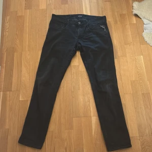 Svarta jeans från Replay - Snygga svarta jeans från Replay med en klassisk femficksdesign. De har en knappgylf och är tillverkade i ett slitstarkt material som ger en bekväm passform. Perfekta för en stilren look.