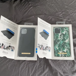 Mobilskal till iPhone 11 PRO MAX - Säljer två snygga mobilskal från iDeal of Sweden. Ett skal är svart och stilrent, medan det andra har ett tropiskt mönster med gröna blad. Helt oanvända endast testade.    150 för ett/ 200 för båda