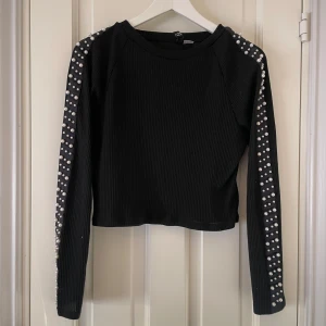 Svart ribbad tröja från H&M - Snygg svart ribbad tröja från H&M. Pärlor längs med ärmarna. Använd ett tiotal gånger.😊Om man vill se hur den ser ut på är det bara och fråga😊