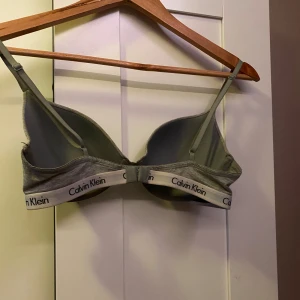 Grå bh från Calvin Klein - Säljer en stilren grå bh från Calvin Klein med justerbara axelband och klassisk logga på resåren. Jättebäkväm men tyvärr för liten för mig. Mycket bra skick och endast testad. Kontakta mig för frågor eller prisförslag.