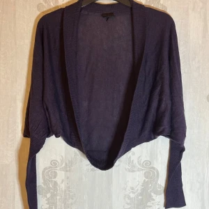 Lila kofta från Cubus - Säljer en stilren lila kofta från Cubus. Den har en öppen design och långa ärmar med ribbade muddar. Perfekt för lager-på-lager-stil och passar till många olika outfits.