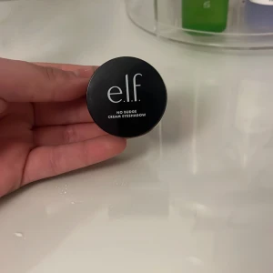 e.l.f. No Budge Cream Eyeshadow - Säljer en krämögonskugga från e.l.f. i en snygg brun nyans. Perfekt för en hållbar look som inte smetar ut. Kommer i en praktisk liten burk som är lätt att ta med sig.